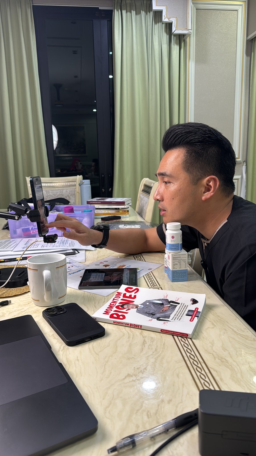 Najib menghadap telefon pada pemegang di meja, dengan buku dan peralatan live di hadapannya